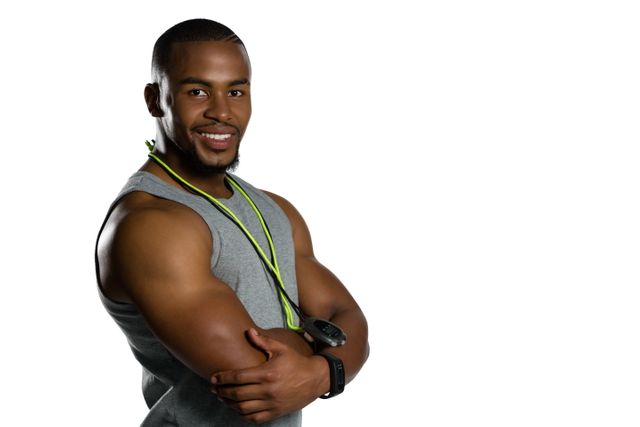 This image depicts a confident male fitness instructor smiling with his arms crossed, wearing a grey tank top and a stopwatch around his neck. Ideal for use in fitness, health, and wellness promotions, gym advertisements, personal training services, and motivational posters.