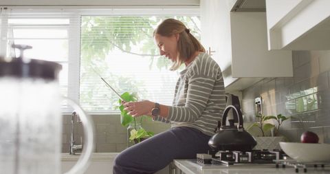 Woman Blowing Kiss on Digital Tablet in Modern Kitchen