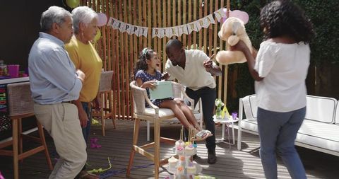 Multigenerational Family Celebrating Child Birthday Backyard Deck with Gifts and Cupcakes
