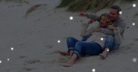 Joyful senior couple relaxing on scenic beachfront dunes