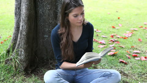 Woman Enjoying Book by Tree in Peaceful Park Setting