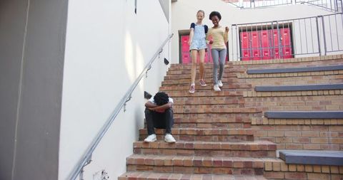 Sad Teen Sits on Stairs Observed by Smiling Schoolmates - Download Free Stock Images Pikwizard.com