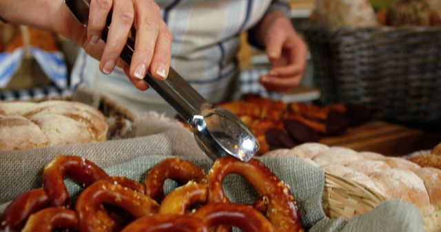Close Up of Hand Picking Freshly Baked Pretzels with Tongs at Bakery - Download Free Stock Images Pikwizard.com