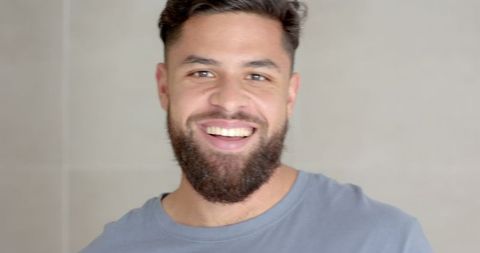 Confident Man Smiling in Casual T-Shirt Against Grey Wall