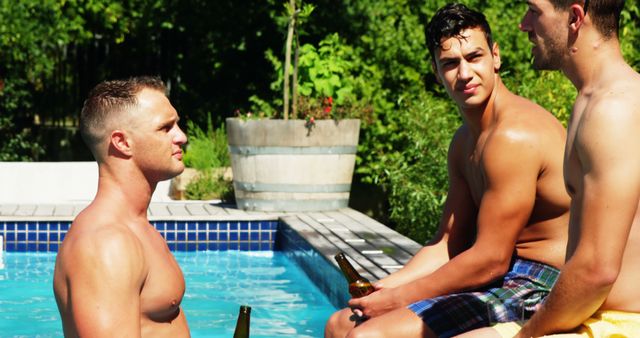 Group of friends spending leisure time by the poolside, drinking beers on a sunny day. Ideal for content related to friendship, summer activities, outdoor leisure, relaxation, and bonding moments.