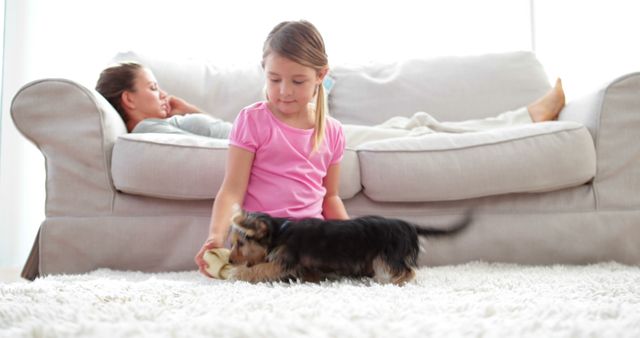 Young Girl Playing with Puppy in Living Room while Mother Resting on Couch - Download Free Stock Images Pikwizard.com