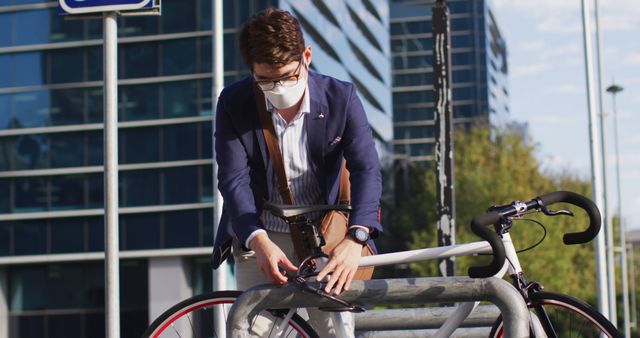 Asian man wearing face mask locking his bicycle at corporate park. health protection and safety during covid-19 pandemic concept
