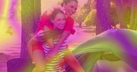 Joyful friends share piggyback ride at vibrant campsite