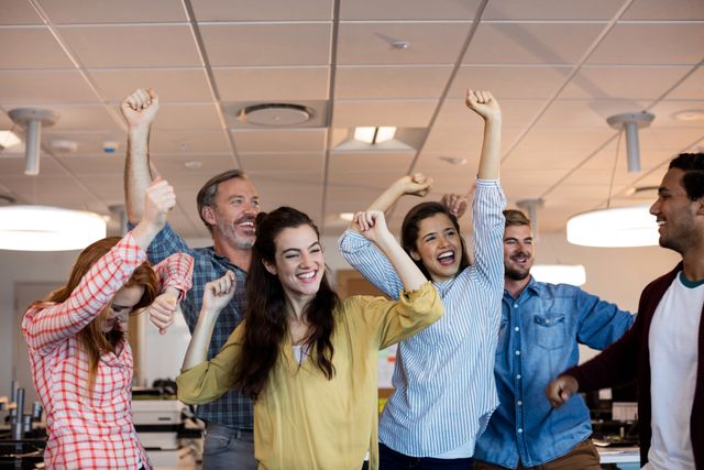 This image shows a joyful business team celebrating a success in a modern office. Ideal for illustrating concepts like teamwork, motivation, professional success, and positive work culture. Great for business blogs, corporate websites, and promotional materials focusing on team spirit and workplace achievements.