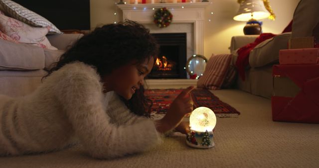 Young Girl Enjoying Festive Snow Globe by Cozy Fireplace - Download Free Stock Images Pikwizard.com