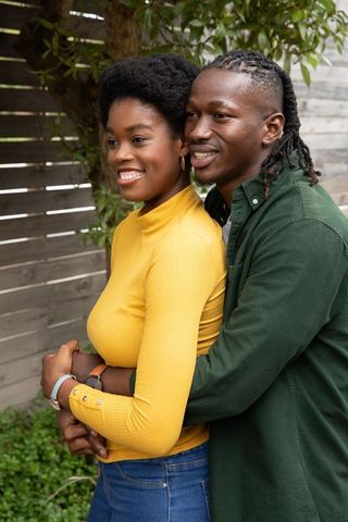 Affectionate couple embracing outdoors amid subtle natural backdrop