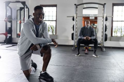 Trainer coaching kneeling athlete wearing smartwatch during strength training session