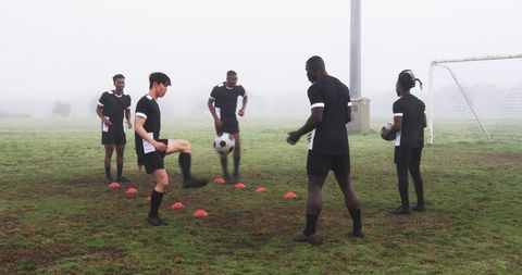 Soccer Players Training on Foggy Field with Cones