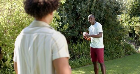 Friends Enjoying Casual American Football Game in Sunlit Backyard
