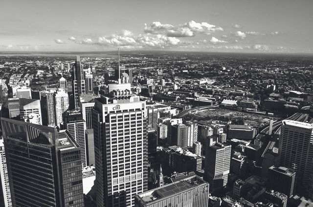 This high-contrast black and white photograph captures an expansive urban cityscape. Skyscrapers and buildings dominate the frame, providing a striking view of an extensive metropolitan area during the daytime. This image is perfect for use in urban studies websites, architectural presentations, city planning materials, and high-definition backgrounds to highlight modern city life and development.
