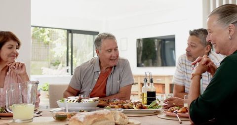 Diverse Friends Enjoying a Meal and Conversation Around Dining Table