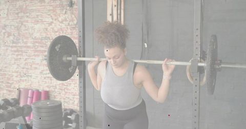 Female athlete performing barbell back squat in industrial gym with digital rep tracking overlay