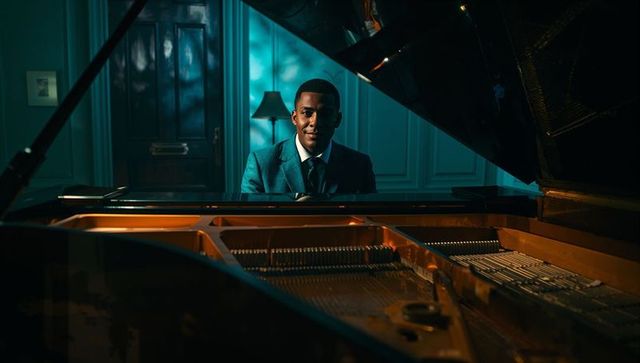Elegantly dressed man playing grand piano in luxurious music room