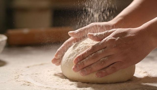 Hands Kneading Dough Ball with Flour Dust for Artisan Bread Making and Rustic Baking