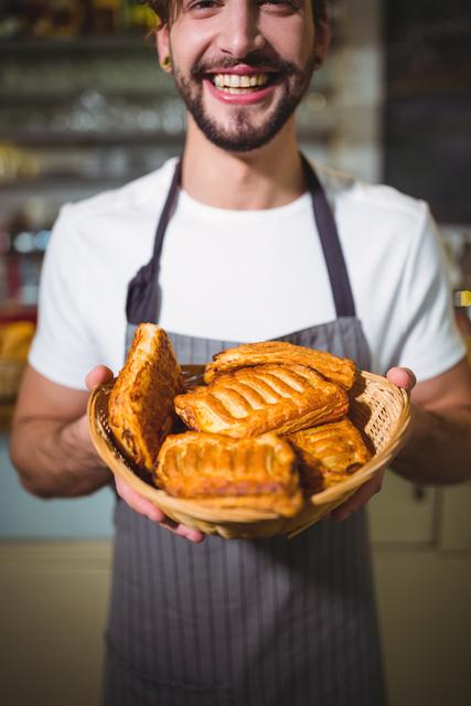 Portrait of smiling waiter holding a basket of bread in cafÃ©