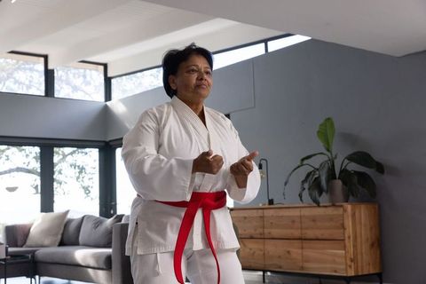 Senior Woman Practicing Martial Arts at Home with Red Belt