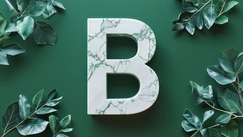 Marble letter b amidst foliage on green background