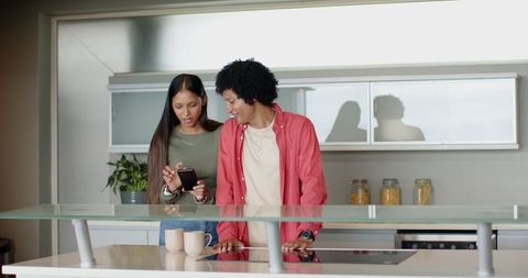 Couple Sharing Smartphone Experience in Modern Kitchen