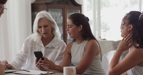 Diverse women discussing wedding plans at home with technology