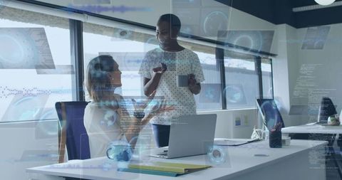 Women collaborating over laptop with holographic interface, modern office teamwork