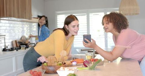 Friends Enjoy Cooking and Socializing in Kitchen with Veggies and Wine