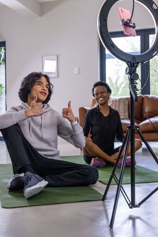 Diverse teens filming home workout with ring light and smartphone for fitness content