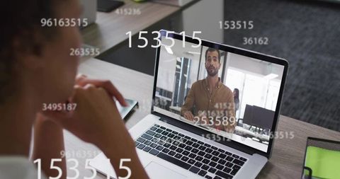 Woman watching remote presentation with floating data overlays on laptop in modern office
