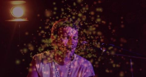 Intimate singer performing under spotlight with golden particles and moody lighting