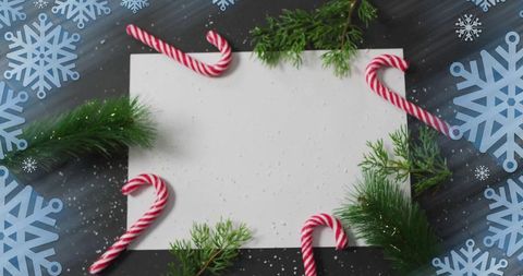 Displaying blank white card on dark wood tabletop with candy canes and pine sprigs