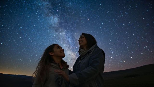 Friends Admiring Night Sky with Milky Way Above Hillside