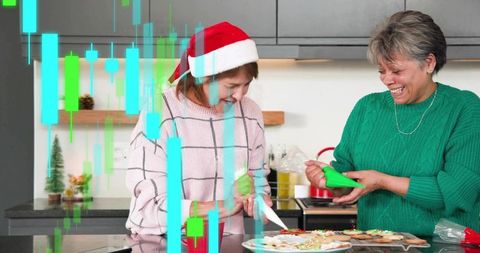 Women decorating holiday cookies on kitchen island wearing santa hat and cozy sweaters