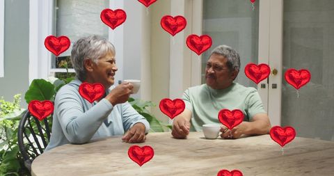 Senior Couple Enjoying Coffee Surrounded by Digital Hearts