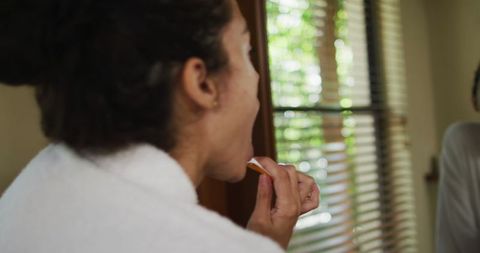 Woman with Vitiligo Practicing Oral Hygiene by Mirror Window
