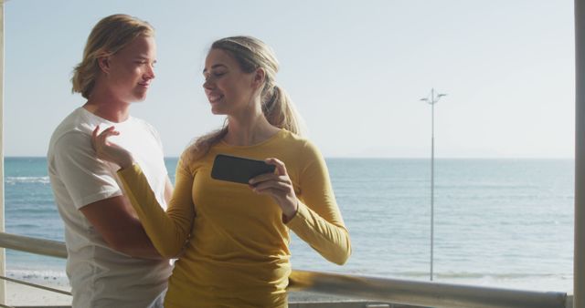 Romantic caucasian couple embracing and taking pictures with smatrphone on beach at sunset. Vacations, communication, romance, love nature and relaxation, unalterned.