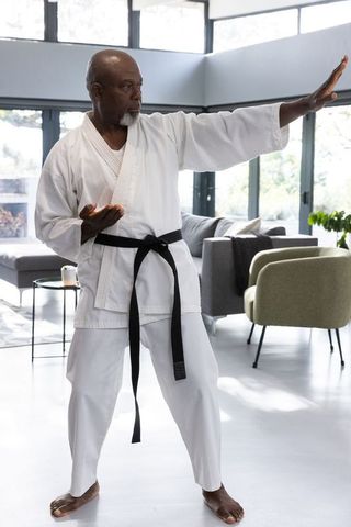 Senior Man Practicing Karate in Modern Living Room Setting