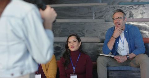 Diverse audience listening and taking notes during conference talk in modern auditorium