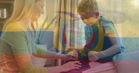 Mother guiding son tapping tablet on sofa with ecuador flag overlay, cozy home learning