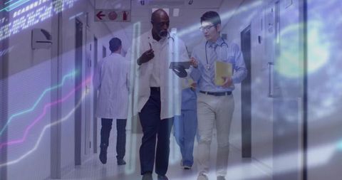 Medical team walking and discussing digital patient data on tablet in hospital corridor