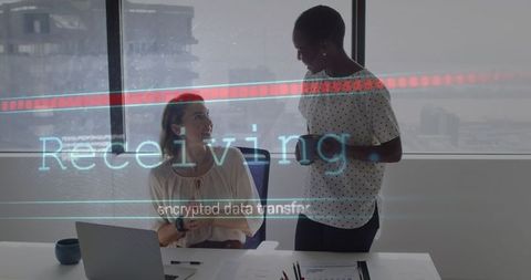 Diverse female coworkers discussing secure data transfer in modern office