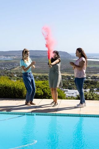 Women Celebrating with Colorful Smoke at Poolside Gathering