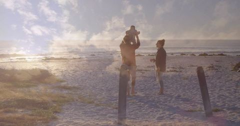 Golden-hour family moment father carrying baby on shoulders at peaceful beach backlit seaside