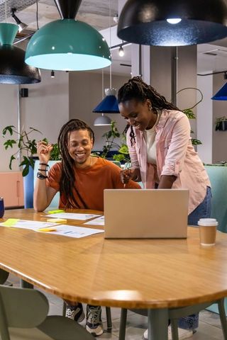 African american coworkers collaborating at laptop, brainstorming in modern coworking space