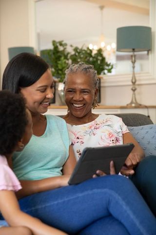 Three Generations of Women Sharing Tablet in Cozy Living Room