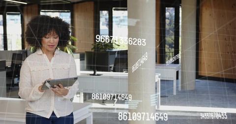 Mid-adult woman analyzing tablet data with ar overlays in modern office interior