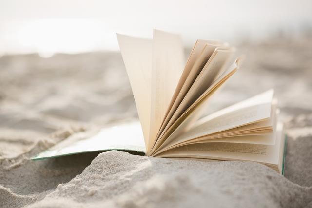 Close-up of open book on sand at beach